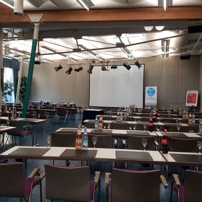 Kleiner Saal in parlamentarischer Bestuhlung mit Blick zur Leinwand